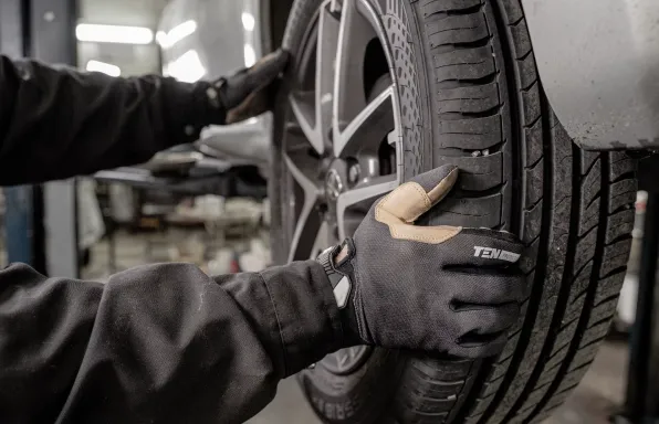 Serviser u rukavicama skida kotač s automobila u radionici